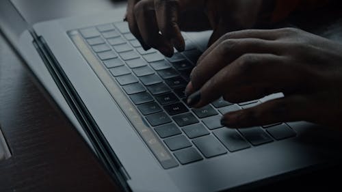 A Woman Typing On A Laptop Keyboard