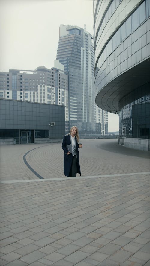 A Woman Walking With A Coffee And Laptop On Hand