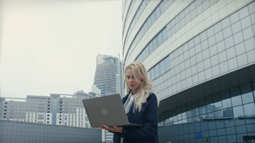 A Woman Using A laptop While Standing Outdoors