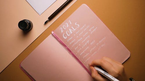 Close-Up View of a Person Writing Her New Year's Resolution