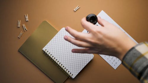 A Person Putting the Ink Pen beside the Paper and Notebook