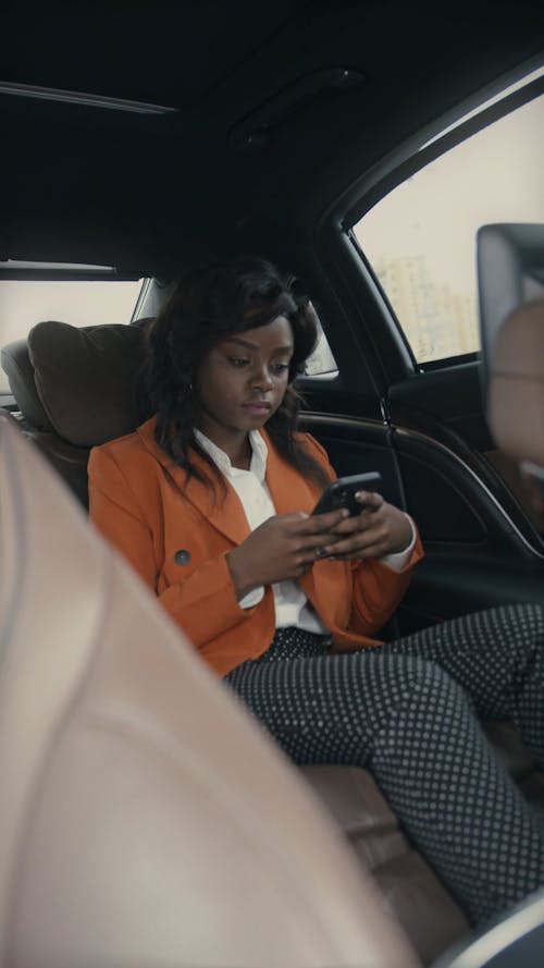 A Woman Using Her Phone Inside A Moving Car