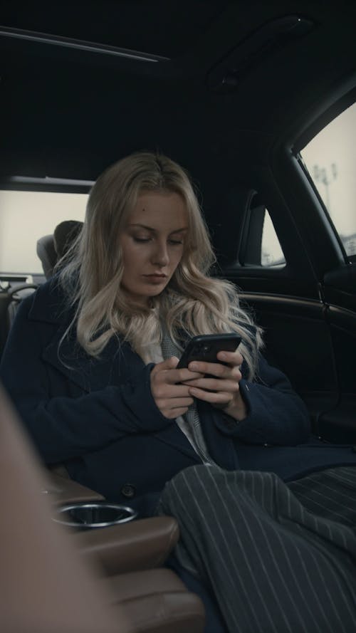 A Female Boss Sitting On The Back Seat Of A Car