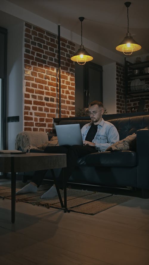 Young Man Sitting on Sofa Using Laptop