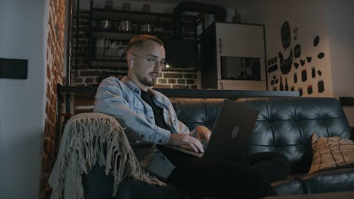 Young Man Sitting on Sofa Using Laptop