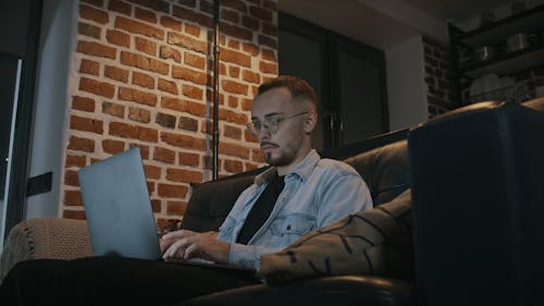 Young Man Sitting on Sofa Using Laptop