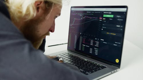 A Man Analyzing Stocks on a Laptop