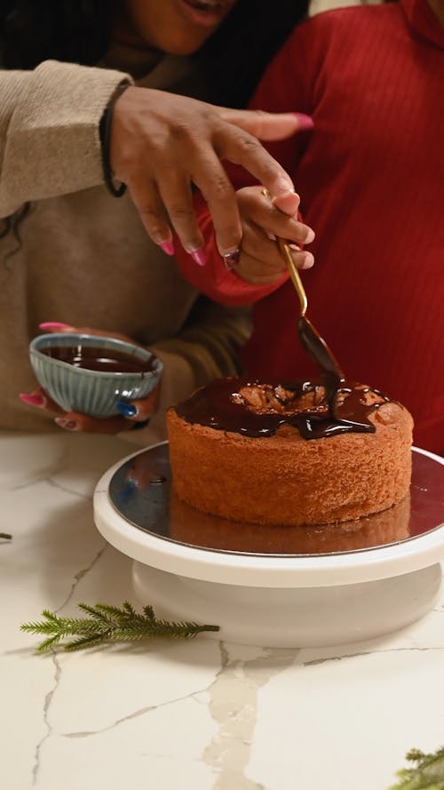 Mom and Daughter Decorating a Cake with Chocolate 