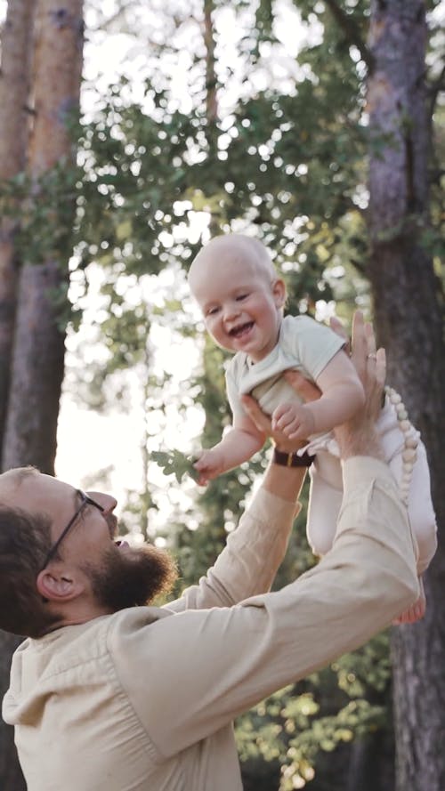 A Bearded Man is Lifting a Baby