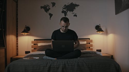 A Man Working with a Laptop in Bed