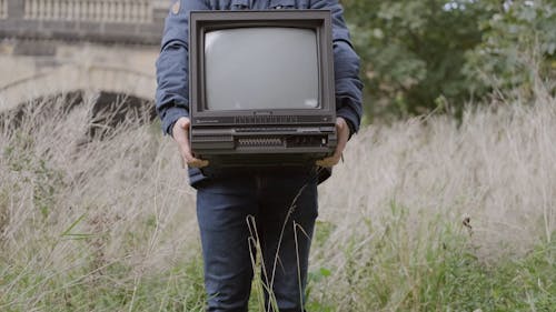 Faceless Person Holding an Antique TV