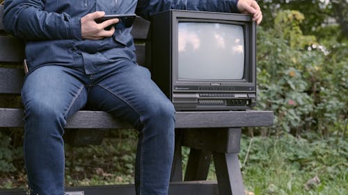 Person Sitting on a Bench while Holding a Television