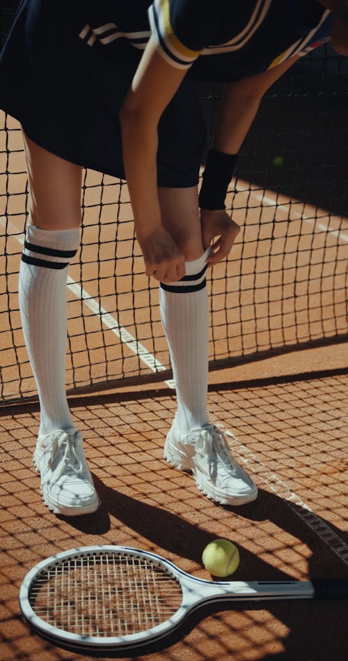 A Female Tennis Player Adjusting her Socks