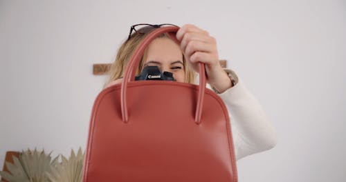 Woman Capturing a Red Bag Using a Canon Camera