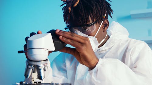 A Man Looking Through the Microscope While Holding the Eyepiece