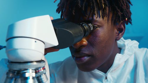 A Man Looking Through the Microscope then Looks at the Camera While Smiling