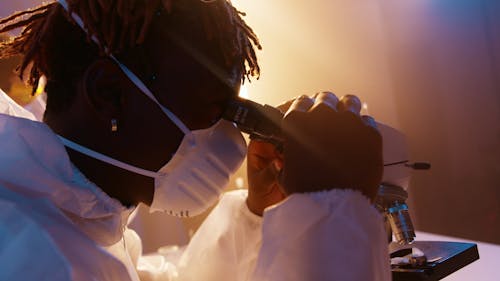 A Man Looking Through the Microscope While Holding the Eyepiece