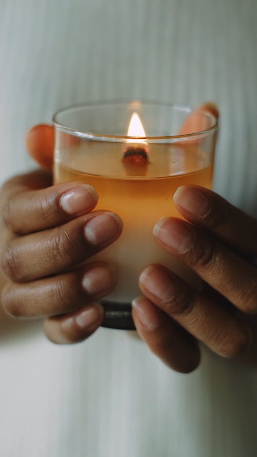 Close-Up View of a Person Holding a Lighted Scented Candle