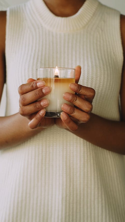 Person Holding a Lighted Scented Candle