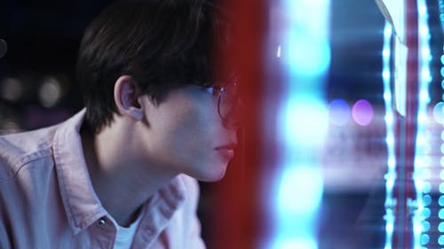 Man in Glasses Playing on an Arcade Machine