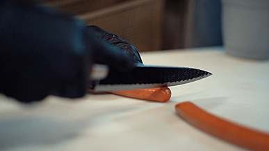 person cutting a frankfurter