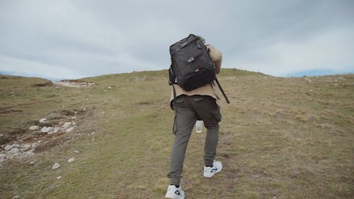 Adventurer Carrying a Backpack Walking on the Hills