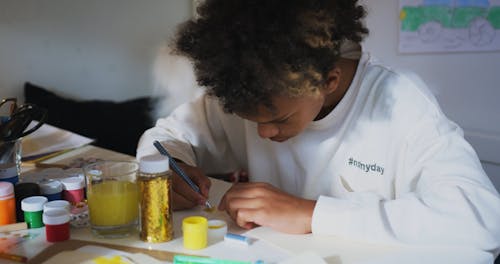 Kid Busy Painting with his Art Materials