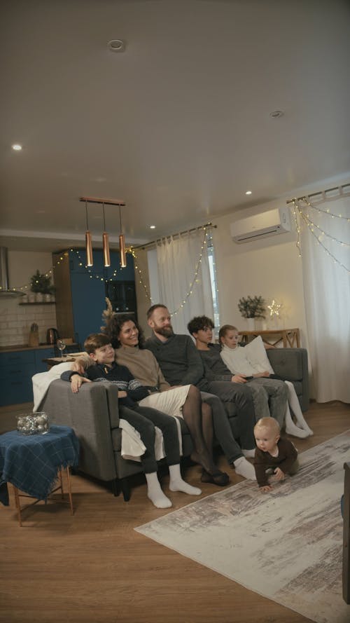 Vertical Video of a Family Watching Together at the Living Room While the Baby is Crawling on the Floor