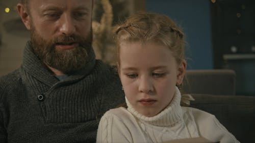 A Close-up Shot of a Father Reading a Book For His Children