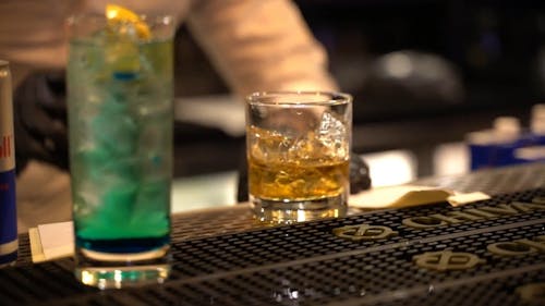 A Bartender Pouring Alcoholic Beverage on a Glass