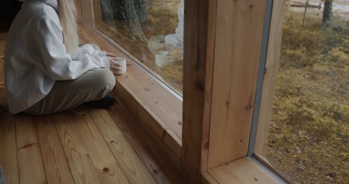 Woman Sitting at Glass Window and Drinking Coffee