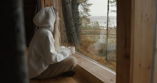 Woman in a Hoodie Watching Through the Window 