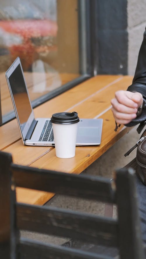 Man Drinking a Cup of Coffee and Typing in a Laptop 