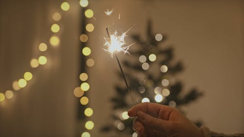 Crop Person Holding a Sparkler on Christmas Background