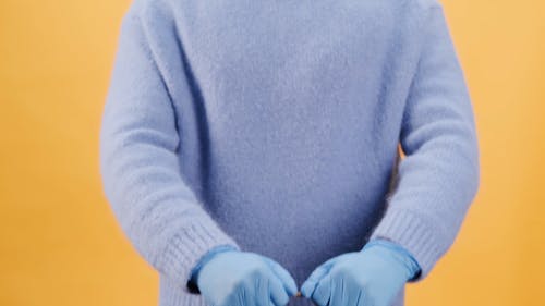 Человек в синем свитере и в перчатках держит сумки для покупок