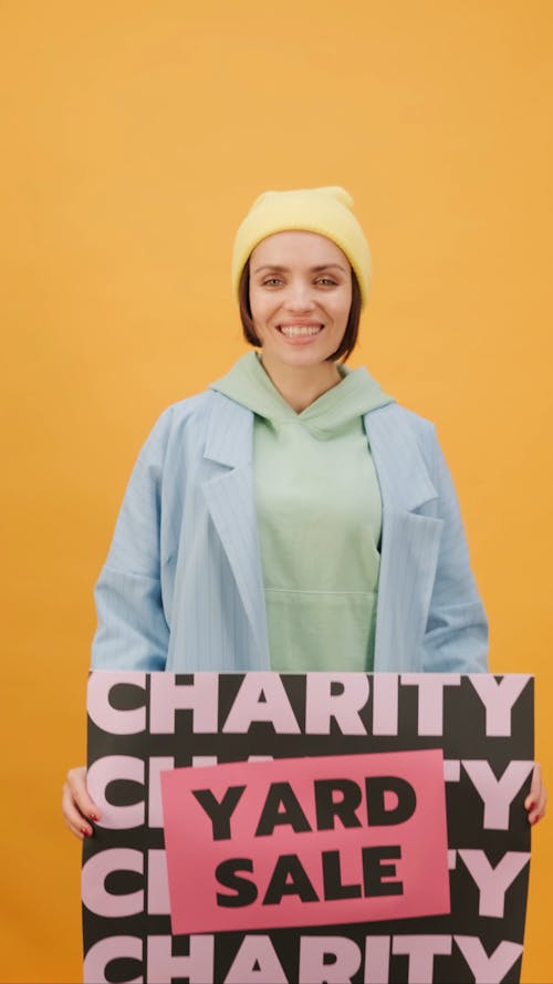 Eine Frau, Die Ein Charity Yard Sale Poster Hält