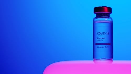 A Close-Up View of a Covid-19 Vaccine Vial on Blue Background