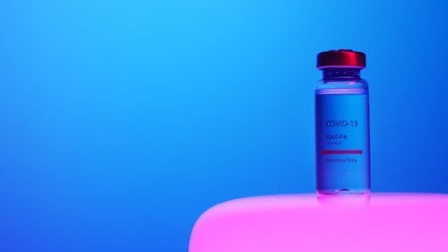 A Close-Up View of a Covid-19 Vaccine Vial on Blue Background