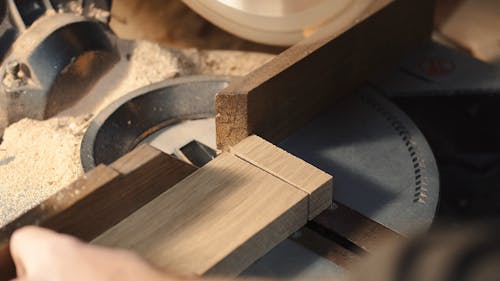 Person Cutting a Plank of Wood Using a Circular Saw