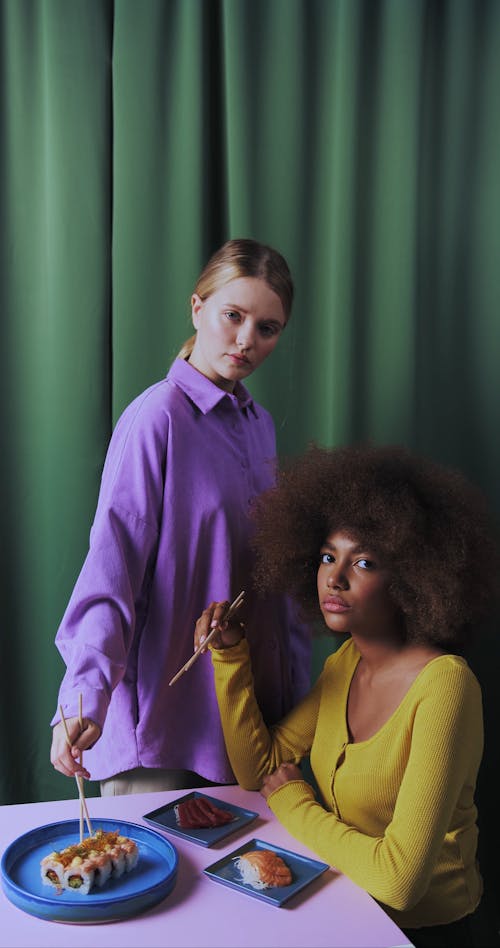 Two Fashionable Women Eating With Chopsticks