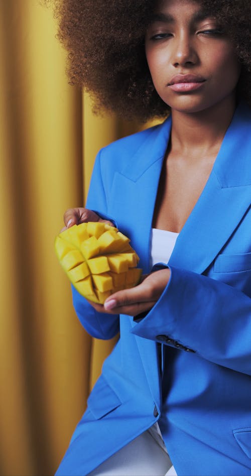 A Person on Blue Suit Holding a Mango