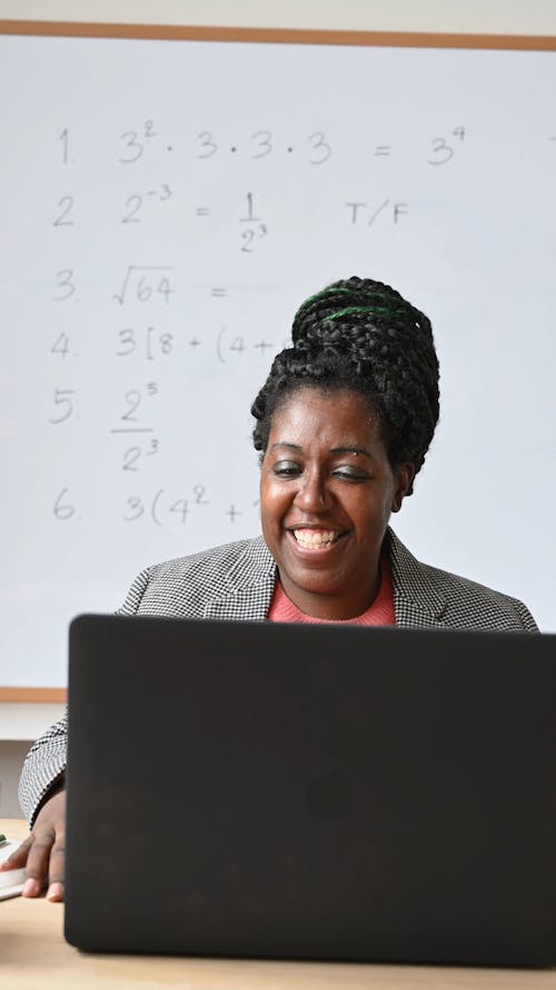 Teacher with Laptop Sitting in Front of Classroom