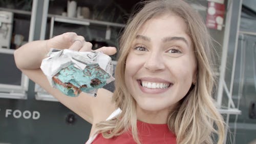 Female Happily Eating a Burger with Colored Bun