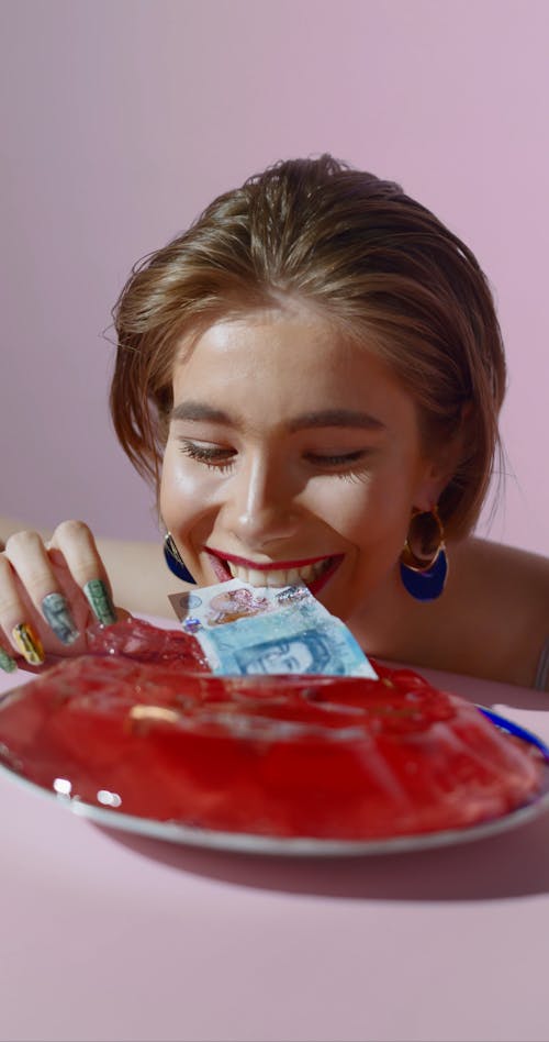 Close-Up Video of a Woman getting and Biting a Banknote From a Jelly