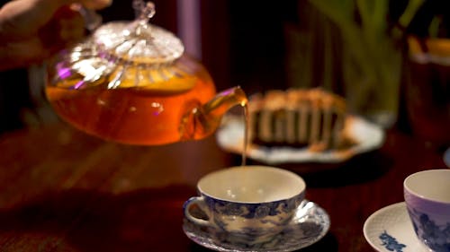 Person Pouring Tea on a Tea Cup