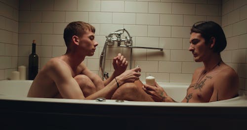 Two Guys Lighting a Candle while in a Bathtub