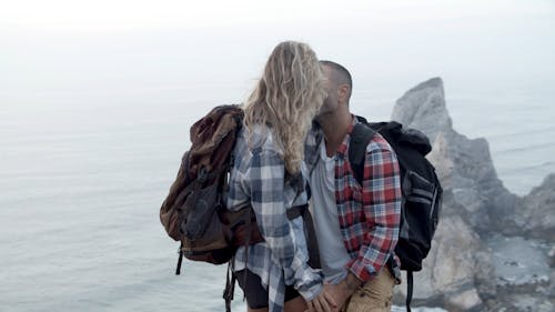 Adventurous Couple Kissing on Cliff by the Ocean