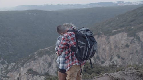 Back View of a Couple Embracing while Standing on the Edge of a Cliff