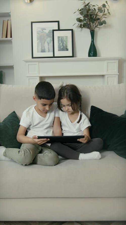 Children Sitting on Sofa Using Digital Tablet