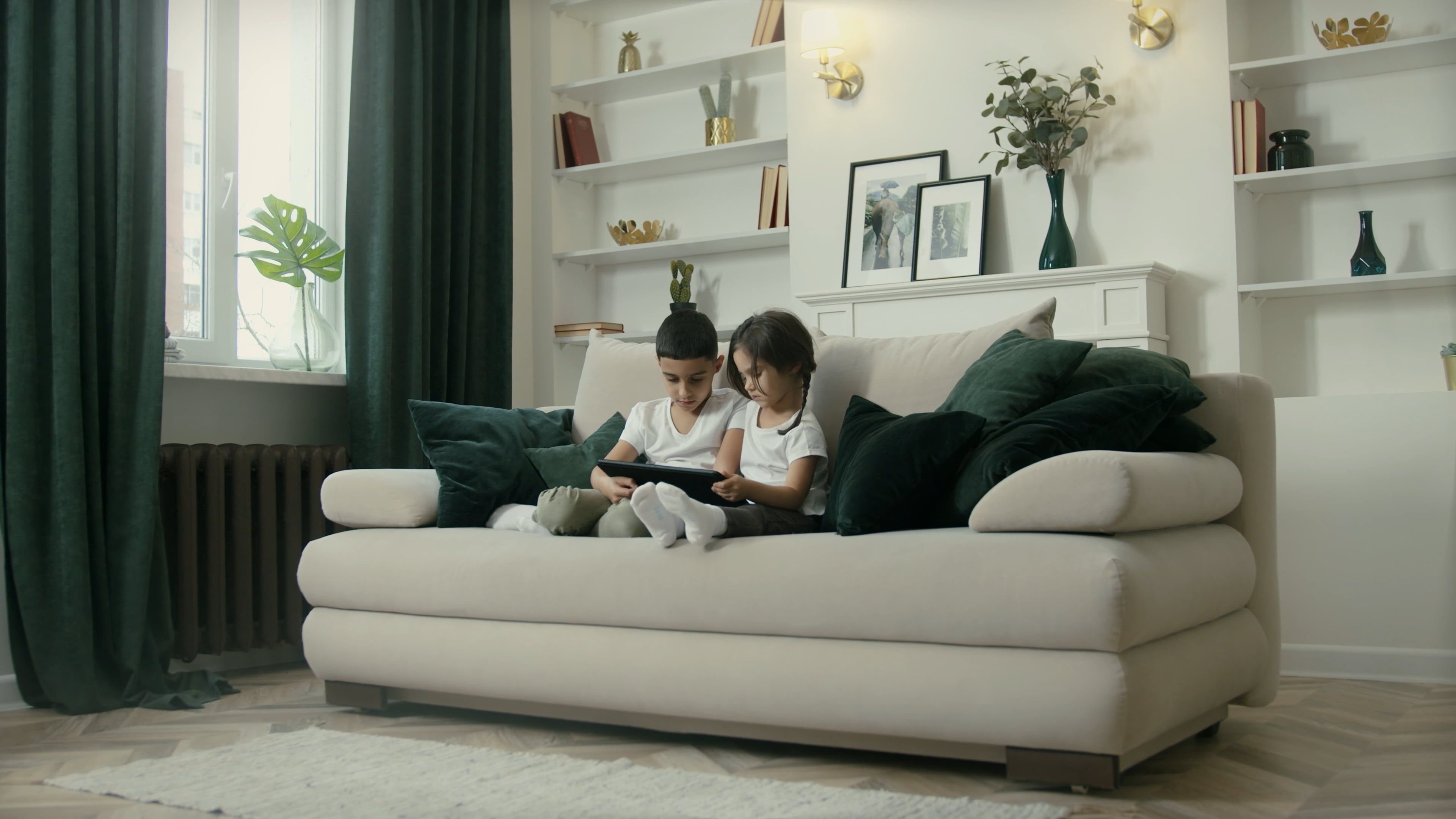 Children Watching at a Tablet while Sitting on a Couch Free Stock Video